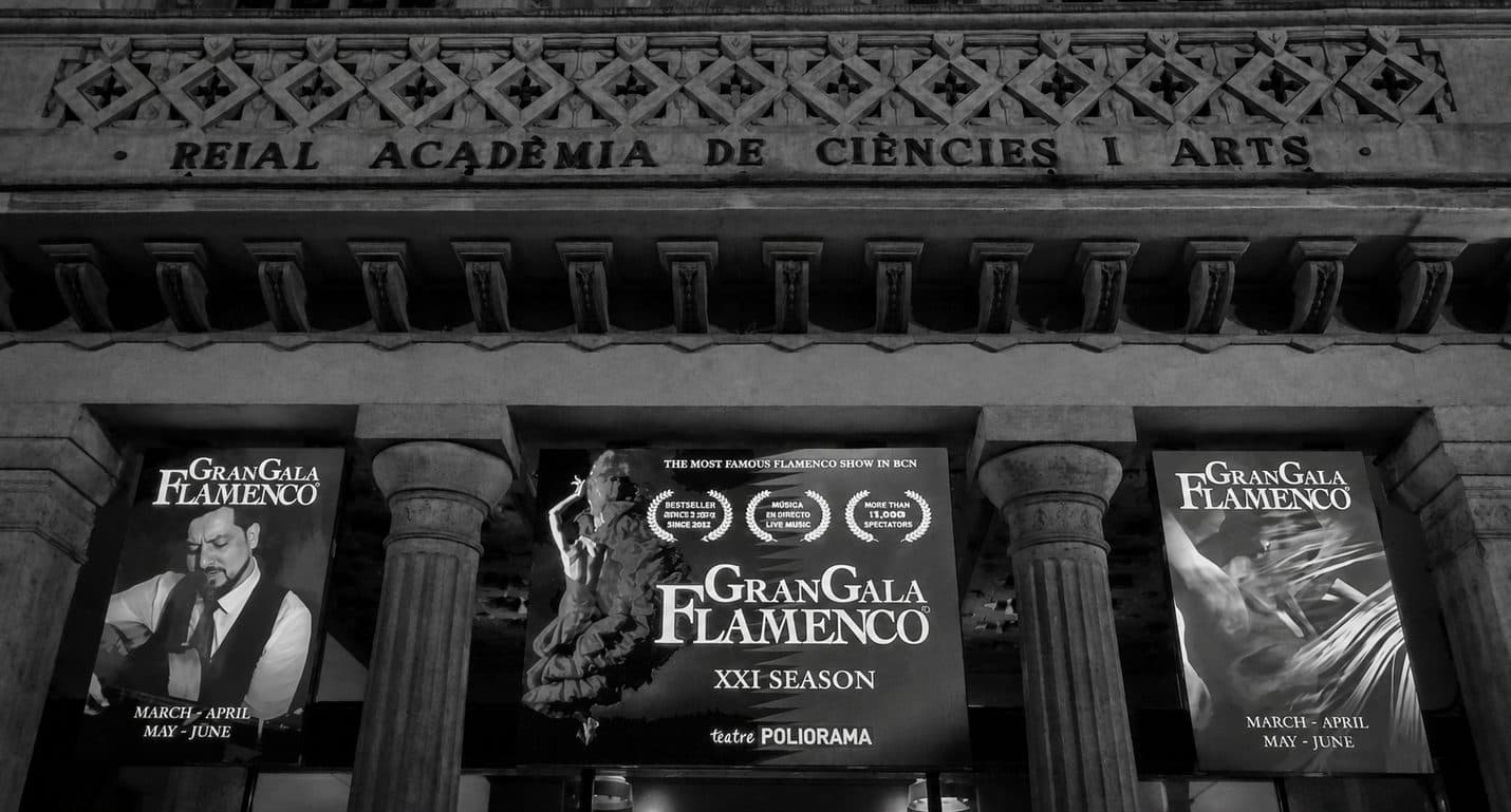 Carteles de Gran Gala Flamenco de su XXI temporada montados sobre la fachada de piedra de la Reial Acadèmia de Ciències i Arts, sede del Teatre Poliorama de Barcelona